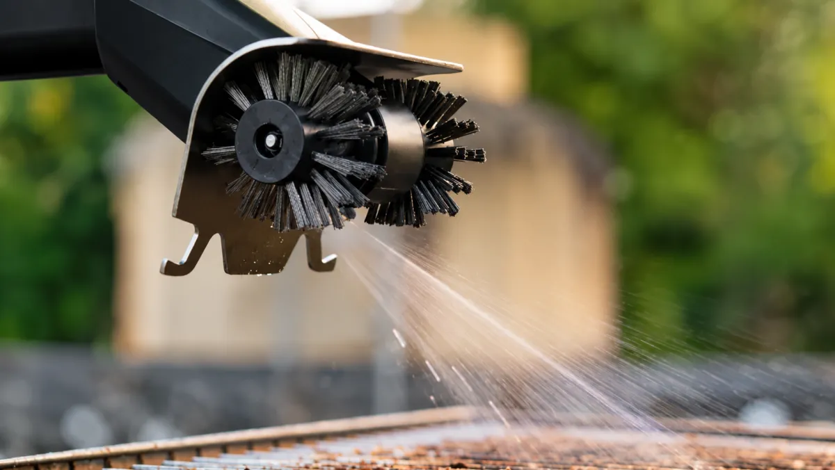 Wamoma GrillMaster spraying water while scrubbing a grill grate